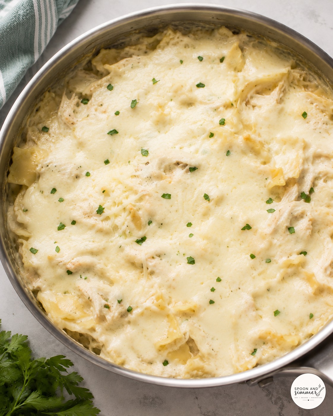 Shredded mozzarella and parmesan melting over noodles in white chicken skillet lasagna